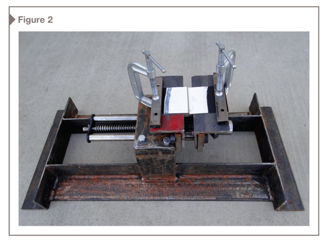A bench vise was modified by welding steel angles to make a frame, and the handle was replaced with a socket to allow smooth opening of the jaws. Coating was applied to a vinyl test substrate and clamped under bars on the jaws.