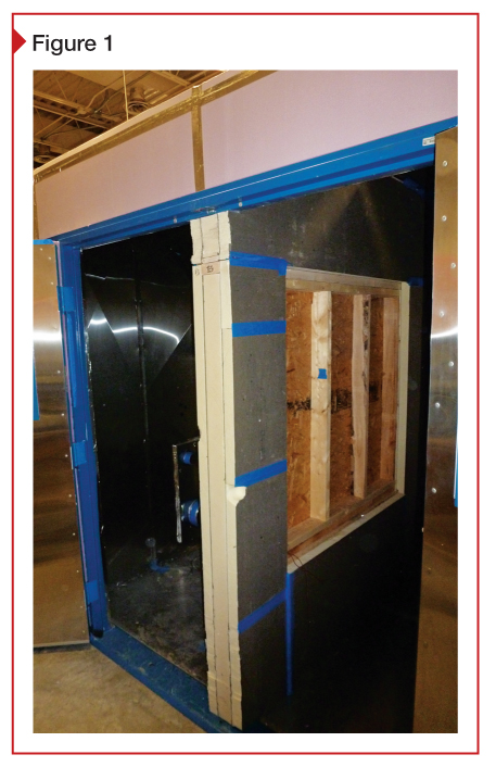 Insulated demising wall in environmental chamber with wall specimen in opening (viewed from stud side). When the chamber doors are closed, one side of the chamber will be heated, and the other ventilated to force heat to flow through the wall specimen.