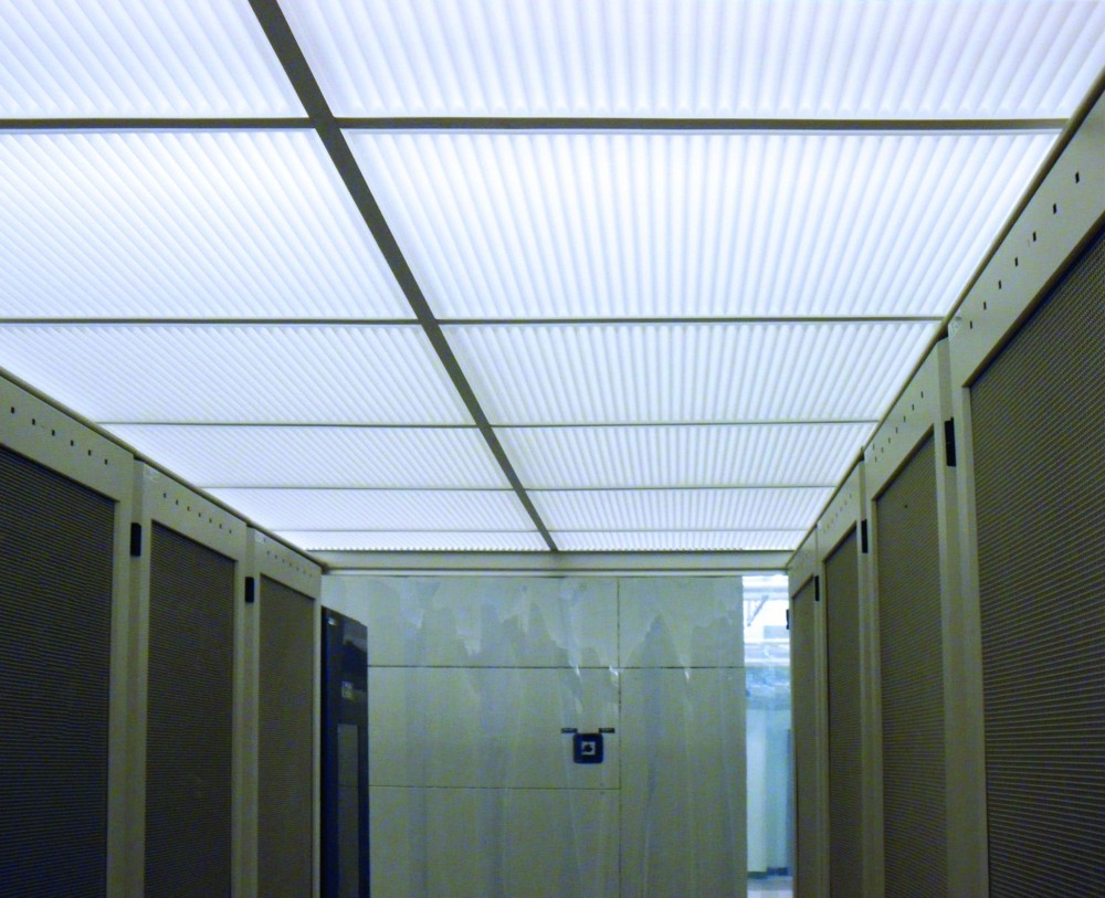 Computer server farms illustrate how thermoformed ceiling products can solve a complex set of requirements. Cool air is typically fed into server racks to keep equipment within an optimal operating temperature range. Instead of releasing heated air into the surrounding room, aisles between racks are enclosed to act as plenums for exhaust air. By using translucent, drop-out panels as above-aisle ceilings, light fixtures and fire sprinklers can be located above server banks where they will not interfere with access to servers.