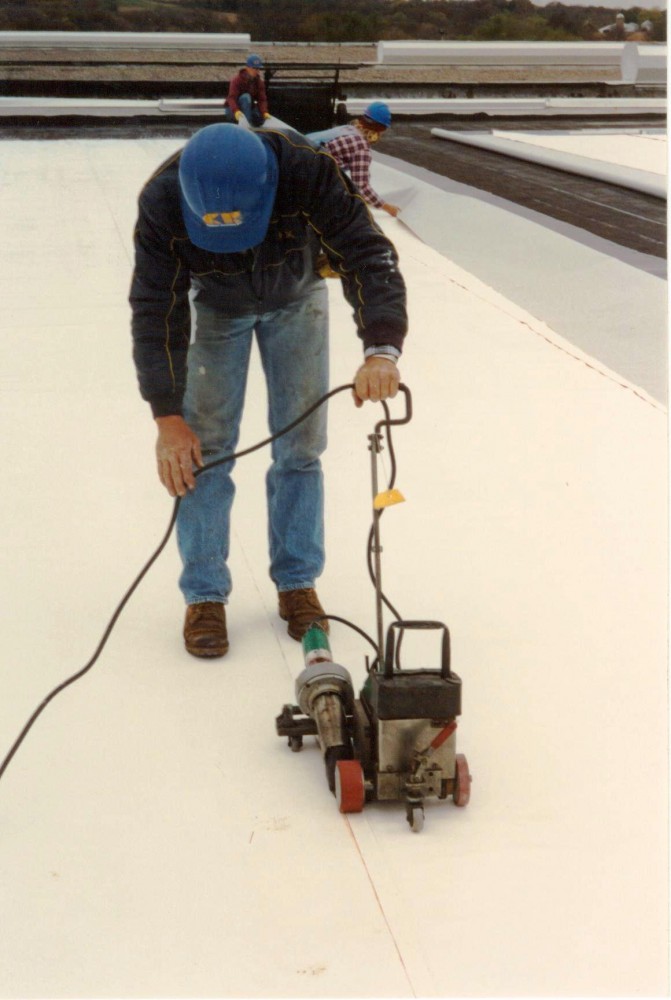 This highly refl ective fl eece-backed PVC is being fully adhered over a multiple ply asphalt BUR and seams are heat welded with an automatic hot-air welder.