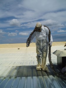 The sprayfoam installer for a roofing application is shown in full personal protective equipment.