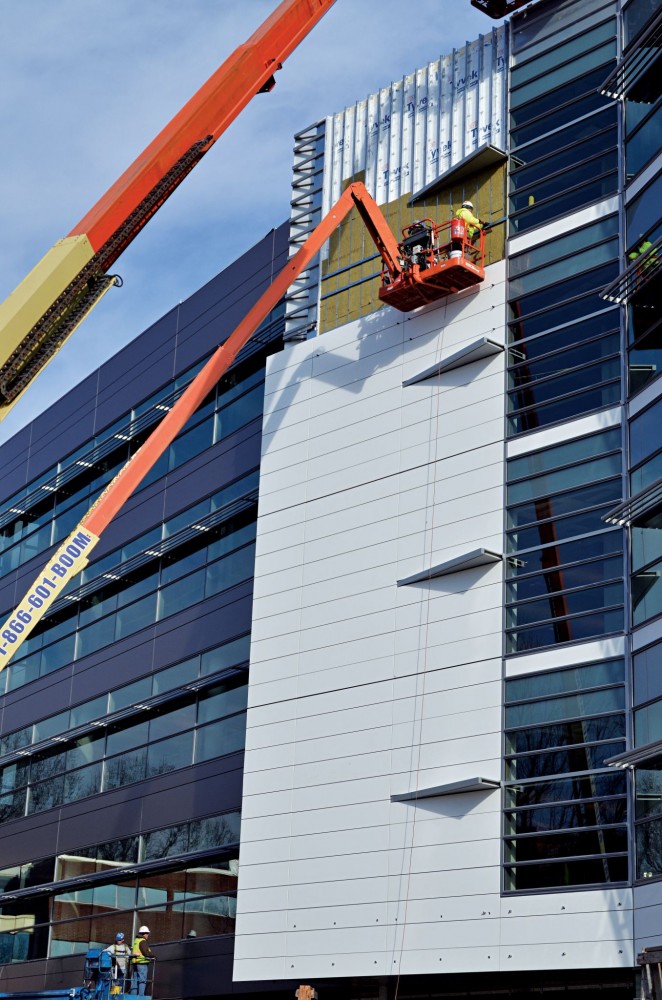 A building wrap air and water barrier system is installed over the exterior sheathing, exterior insulation is installed over the air barrier, and exterior cladding (brick, metal panels, and solid surfacing) are installed to the outside.
