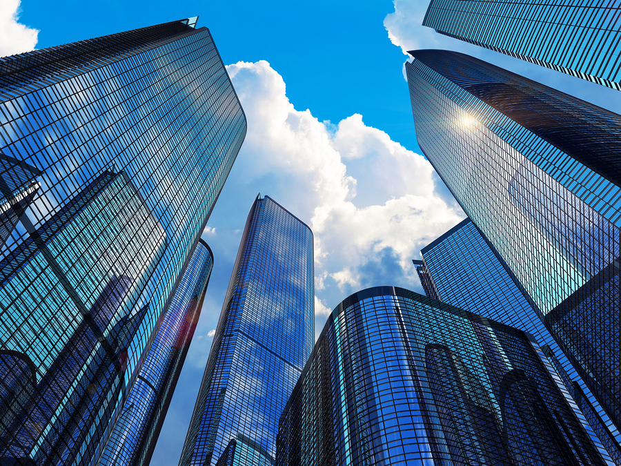 Downtown corporate business district architecture concept: glass reflective office buildings skyscrapers against blue sky with clouds and sun light