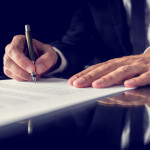Retro image of lawyer signing important legal document on black desk. Over black background.