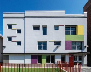 The main façade of UPK K491 has been entirely recreated with new window openings, entrances, and stucco. The rear yard has also been converted into a play space.