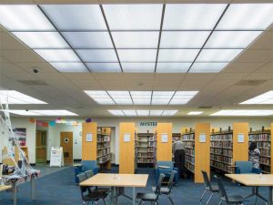 Figure 12: In addition to providing diffused overhead lighting, these luminous thermoformed ceiling panels create scale within the overall plane of the library’s opaque mineral fiber ceiling. The ceiling grid members run continuously through both ceiling panel types
in order to unify overall composition. Photo © Steve Miller