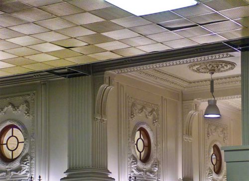 Figure 13: A suspended ceiling was a practical way to install new lighting
and air distribution in Seattle’s King Street Station in 1967. Tastes
had changed and the suspended ceiling was removed to expose
the ornamental ceiling in 2010. The panels that are not seated properly were probably raised to provide access to the above-ceiling cavity, but were difficult to manipulate and reposition correctly due to their stiffness. Photo © CC BY-SA 1.0 by Bachcell