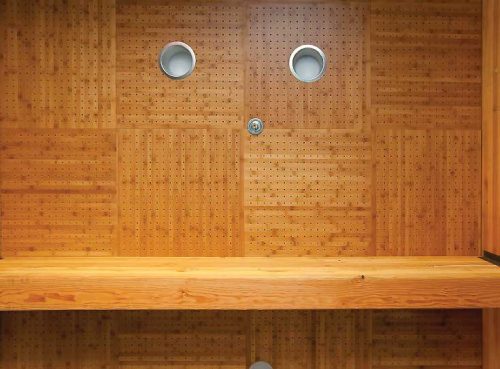 Figure 4: Ceiling panels with real wood veneers are available with a variety of Class A-rated cores or on metal. Faux-wood finishes are available on thermoformed and metal panels. These panels are perforated to boast their sound attenuation average (SAA) and have grooved edges to cover the ceiling suspension grid. The grain direction in adjacent panels are rotated for a decorative checkerboard effect. While the light fixtures are centered in panels, the sprinkler is not. The awkward appearance of sprinklers can be avoided with drop-out panels.