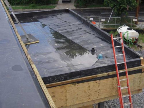 Figure 5: Pull-back view of water trapped between RTUs looking east. Note the lack of a roof drain and/or a well-defined waterway. Ponded water can also be observed in the background.