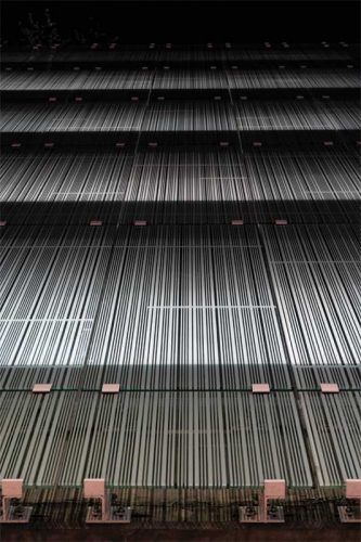 Illuminated by the parking’s interior lighting, the white pattern-fritted glass appears to glow.