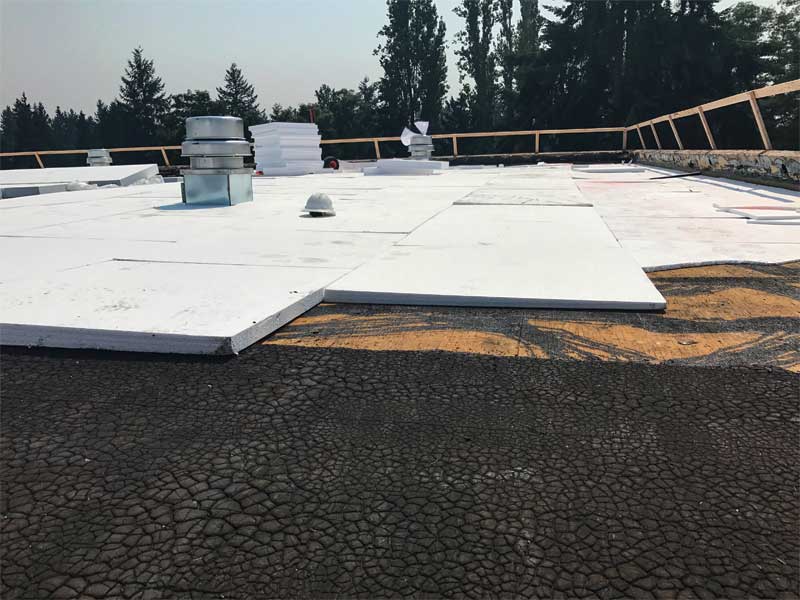 A white tapered roofing system being installed on a flat roof. 