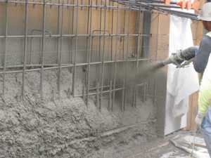 Shotcrete being applied to form a structural reinforced blind-side wall.