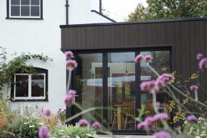 The photo focuses on composite cladding, which resembles dark-colored wood, on a portion of a residence.