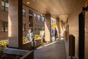 A man sits in an open-air lobby of Heartwood, which utilizes mass timber in its structure.