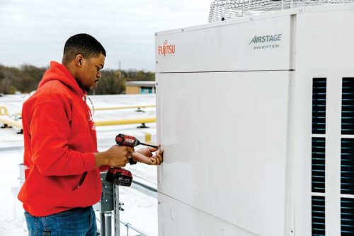 A man reassembling a variable refrigerant flow (VRF) system unit after servicing it.