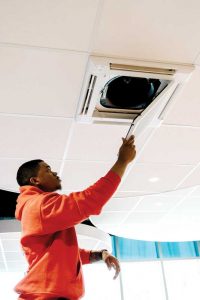 Man nstalling a filter cartridge in the ceiling cassette unit.