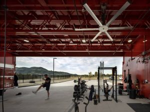 Firemen exercising at gym equipment placed in the multipurpose open-air apparatus bay.