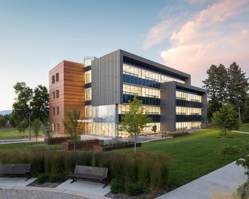 Modern university building at dusk with landscaped grounds.