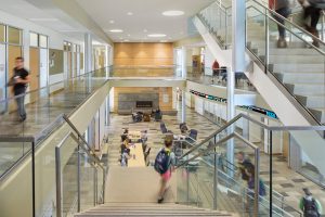 University building interior with stairs, students, and seating area.