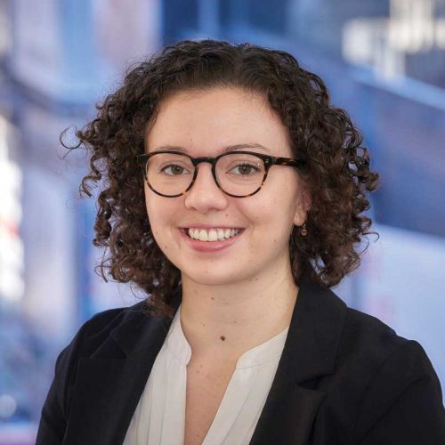headshot of a spectacled woman with curly hair