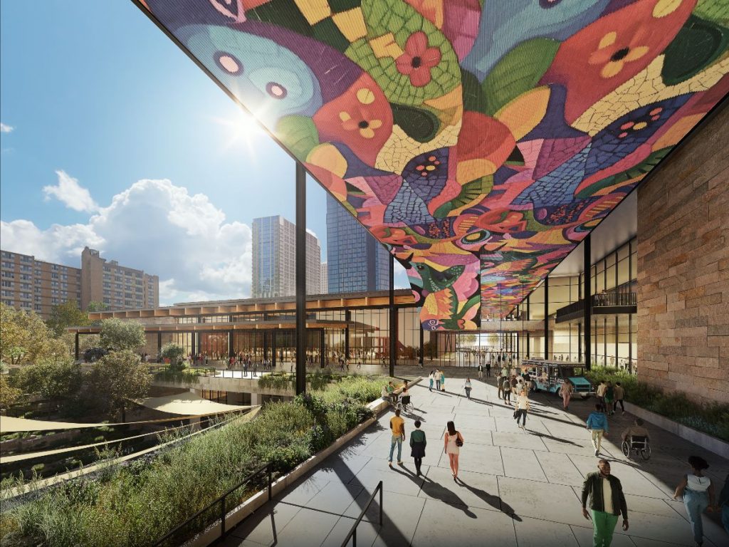 A modern architectural space featuring vibrant ceiling art, sunlit walkways, and people enjoying the outdoor area amidst greenery.