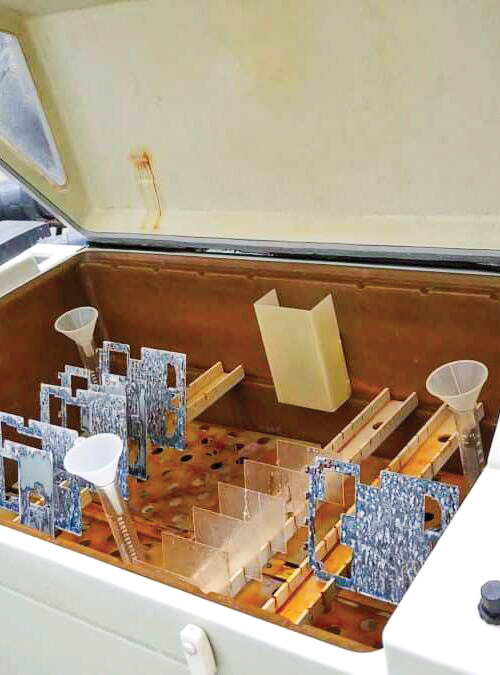 Open container with various laboratory equipment including funnels and plastic dividers, designed for storage or organization of samples.