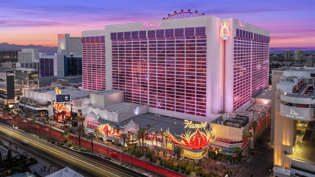 Aerial view of the Flamingo hotel in Las Vegas, adorned with vibrant lights and a beautiful sunset backdrop, highlighting its iconic design.