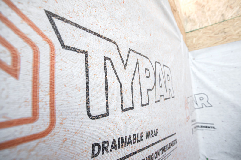 Close-up of a Typar Drainable Wrap, showcasing branding against a textured white background, used in construction for moisture management.
