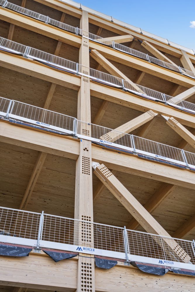 Close-up of a multi-story wooden building's structural beams, showcasing modern design elements and safety railings.