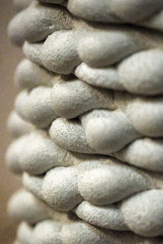 Close-up of textured, rounded gray forms stacked in layers, resembling smooth stones or sculptural elements.