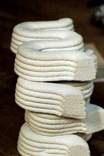 A stack of neatly coiled, textured white material resembling thick rope or clay, showcasing layered, rounded edges.