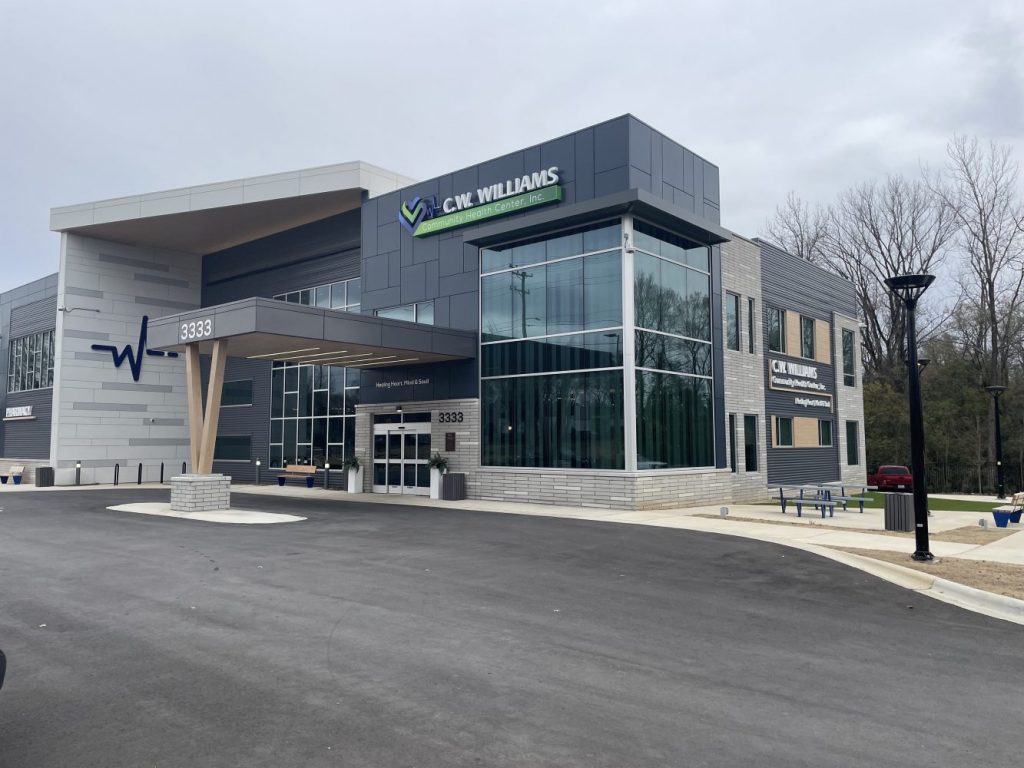 Modern healthcare building with large glass windows, sign reading "C.W. Williams Community Health Center," and a covered entrance at 3333.