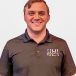 Matt DiNorca stands against a plain background, wearing a black polo shirt with the logo "UMI The Source" prominently displayed.