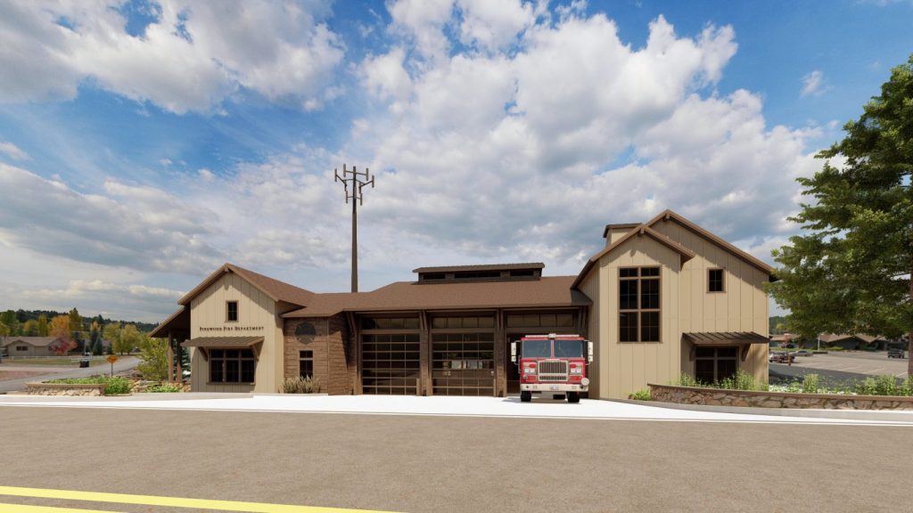 A modern fire station with a red fire truck parked outside, surrounded by greenery and set against a cloudy sky.