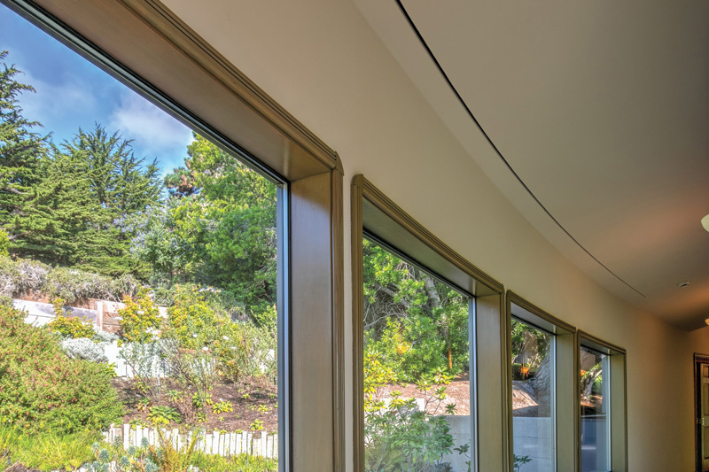 Large windows frame a view of lush greenery and trees, creating a bright and inviting indoor atmosphere.