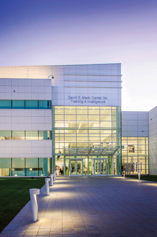 Modern building facade of the David S. Mark Center for Training & Intelligence, featuring large glass doors and a sleek design at dusk.