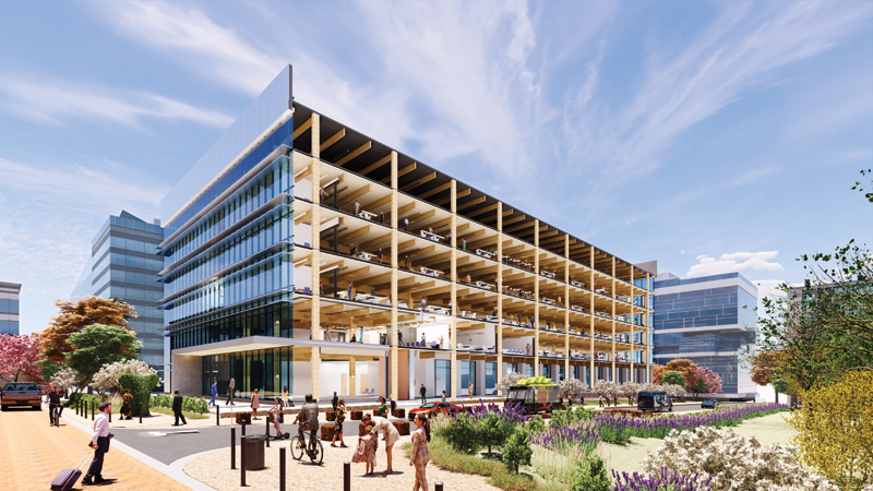 A modern, multi-story office building with glass and wooden elements, surrounded by people and landscaped greenery under a blue sky.