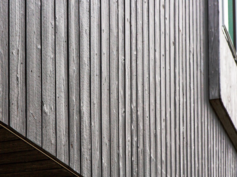 Close-up of a textured wooden wall with vertical planks, showcasing natural grains and a weathered gray finish.