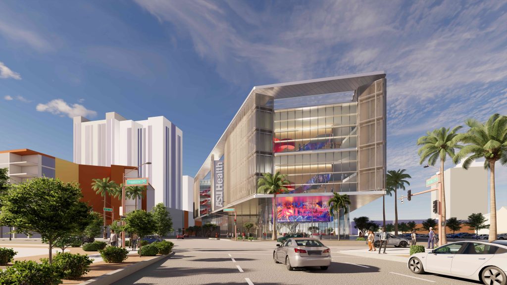 Wide-angle view of a modern building with glass facades, vibrant digital displays, and palm trees lining the street. Cars and clear skies enhance a lively urban scene.