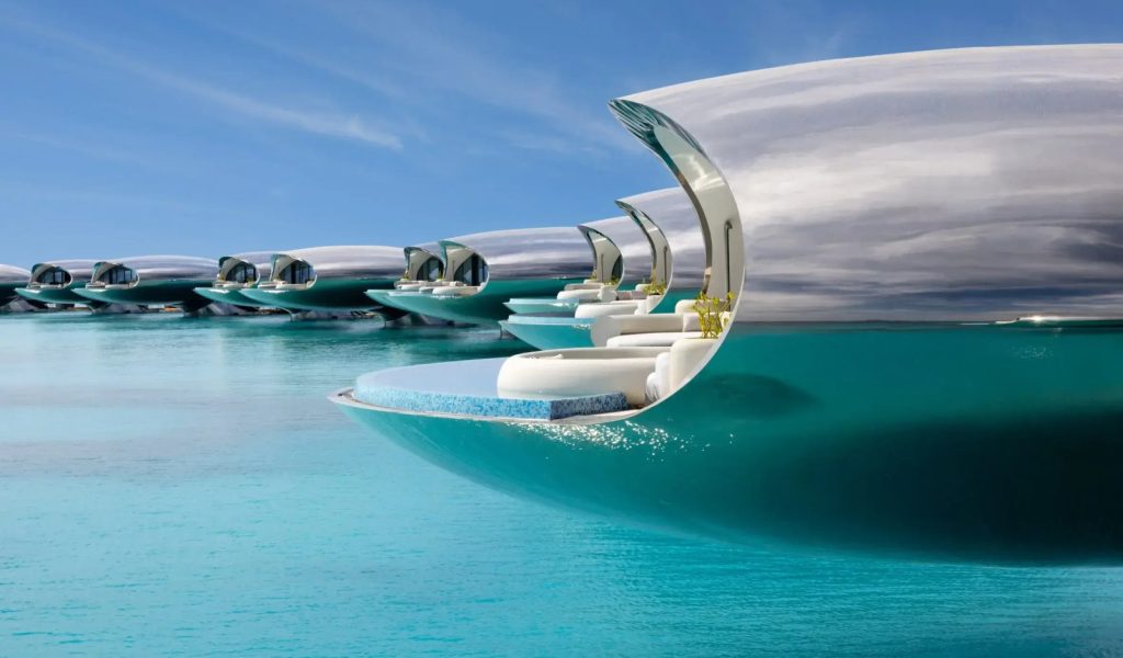 Futuristic accommodation pods with reflective exteriors are positioned in turquoise water, featuring white lounge chairs and plants inside.