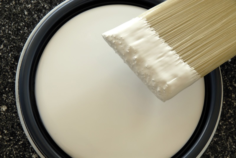 A paintbrush with white paint on it.