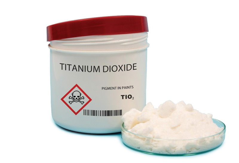 White titanium dioxide powder in a small glass container, showcasing its fine texture and bright color.