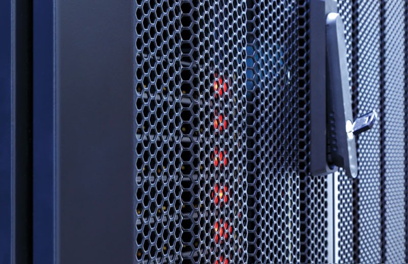 Close-up of a server cabinet with a hexagonal mesh panel and red LED lights, featuring a metallic handle on the side.