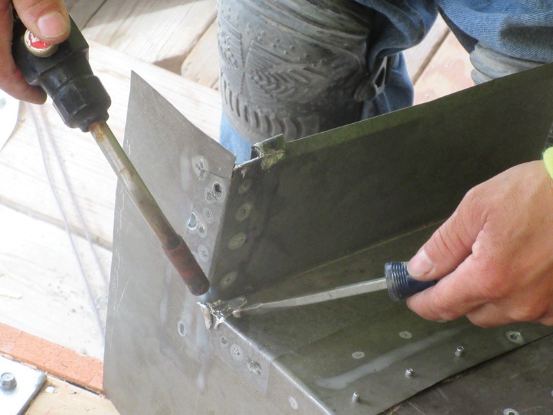Person using hand tools to join riveted sheet-metal panels.